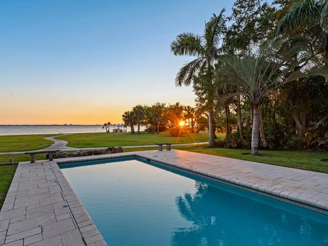 4521 Bay Shore Rd, Sarasota, FL 34234 - pool at dusk featuring a lawn, a water view, and an outdoor pool