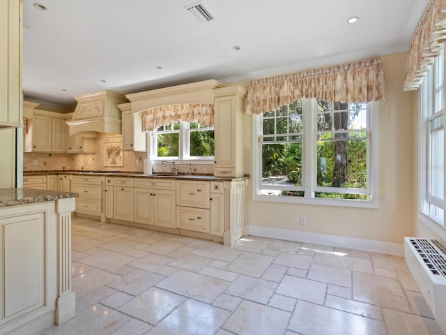 4521 Bay Shore Rd, Sarasota, FL 34234 - kitchen featuring stone tile floors, baseboards, custom range hood, cream cabinetry, and dark stone counters