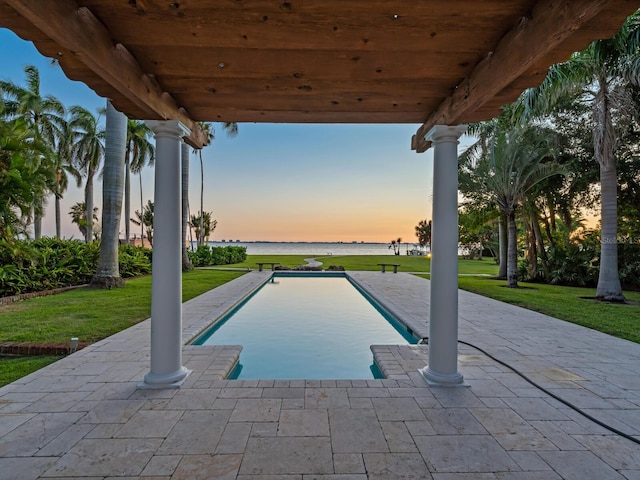 4521 Bay Shore Rd, Sarasota, FL 34234 - pool at dusk featuring an outdoor pool, a water view, a patio area, and a lawn