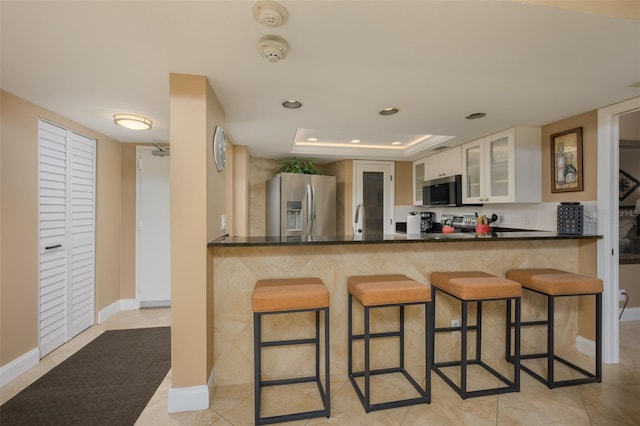 5920 Midnight Pass Rd Unit 104, Sarasota, FL 34242 - kitchen with stainless steel appliances, a tray ceiling, a sink, a kitchen bar, and recessed lighting