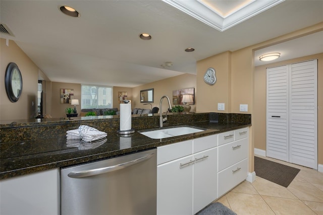 kitchen with sink, white cabinets, stainless steel dishwasher, dark stone countertops, and light tile patterned flooring