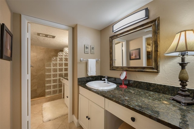 bathroom with tile patterned floors, vanity, and tiled shower