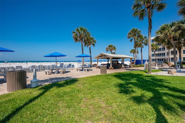 view of home's community featuring a view of the beach, a water view, and a lawn