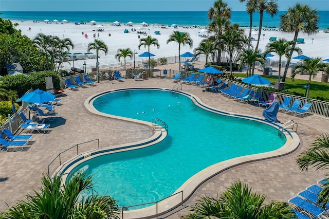 view of pool featuring a beach view, a patio, and a water view