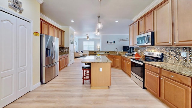 kitchen with stainless steel appliances, a center island, light wood-type flooring, and crown molding