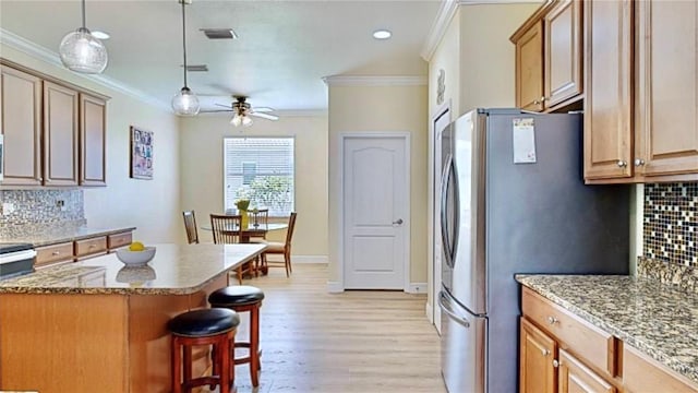 kitchen with decorative light fixtures, ceiling fan, tasteful backsplash, and light wood-type flooring