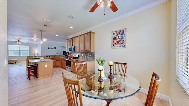 dining room with ceiling fan, light wood-type flooring, sink, and ornamental molding