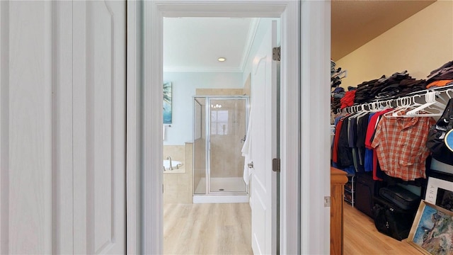 bathroom with a shower with door, ornamental molding, and hardwood / wood-style floors