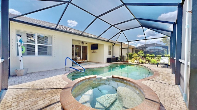 view of swimming pool with ceiling fan, a patio area, glass enclosure, and an in ground hot tub