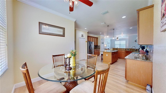 dining space featuring ceiling fan, crown molding, light wood-type flooring, and sink