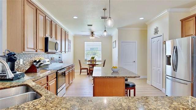 kitchen with a kitchen island, stainless steel appliances, hanging light fixtures, tasteful backsplash, and light wood-type flooring