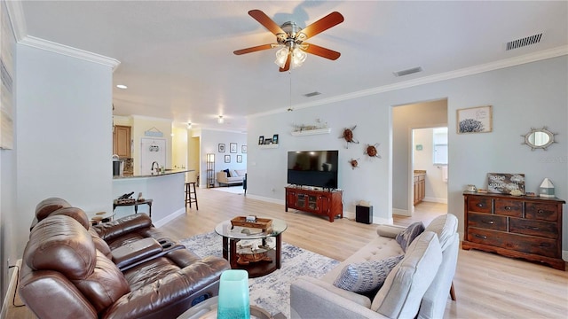 living room featuring ceiling fan, light wood-type flooring, and crown molding