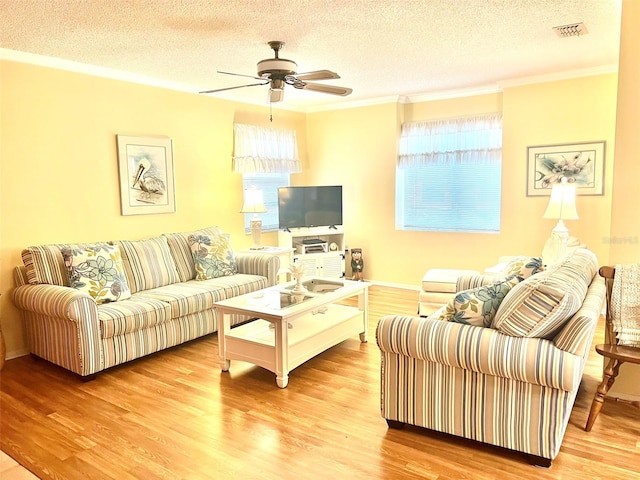 living room with a textured ceiling, ceiling fan, ornamental molding, and wood-type flooring