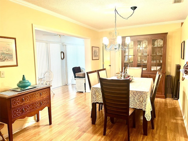 dining space with light hardwood / wood-style floors, crown molding, and an inviting chandelier