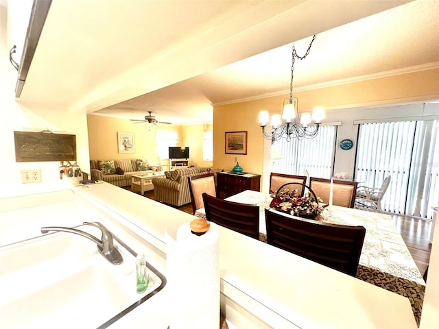 dining space with ceiling fan with notable chandelier, sink, plenty of natural light, and ornamental molding