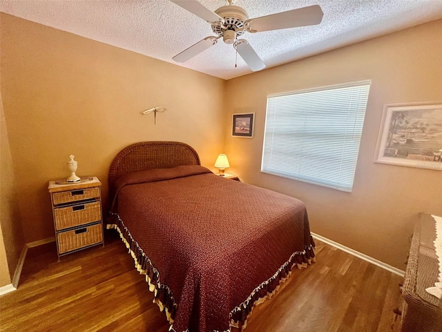 bedroom with ceiling fan, a textured ceiling, and dark hardwood / wood-style flooring