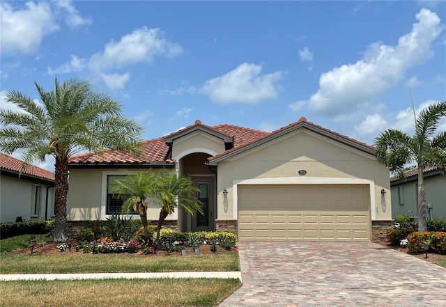 mediterranean / spanish-style home featuring decorative driveway, a tile roof, an attached garage, and stucco siding