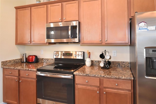 kitchen featuring appliances with stainless steel finishes and dark stone countertops