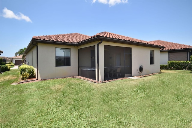 rear view of house with a sunroom, a tile roof, and a yard