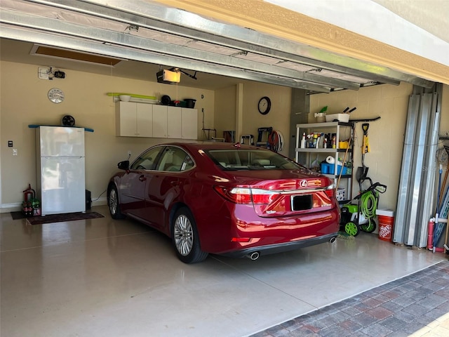 garage with a garage door opener and freestanding refrigerator