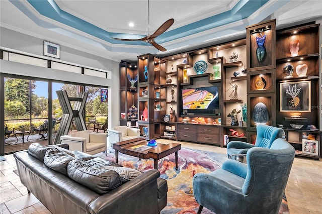 tiled living room with ornamental molding, ceiling fan, and a tray ceiling