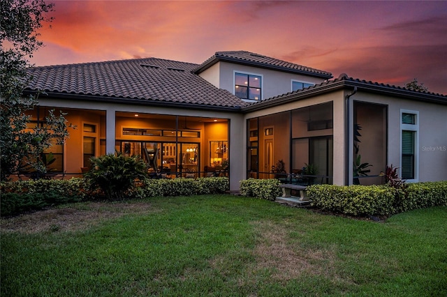 back house at dusk with a lawn