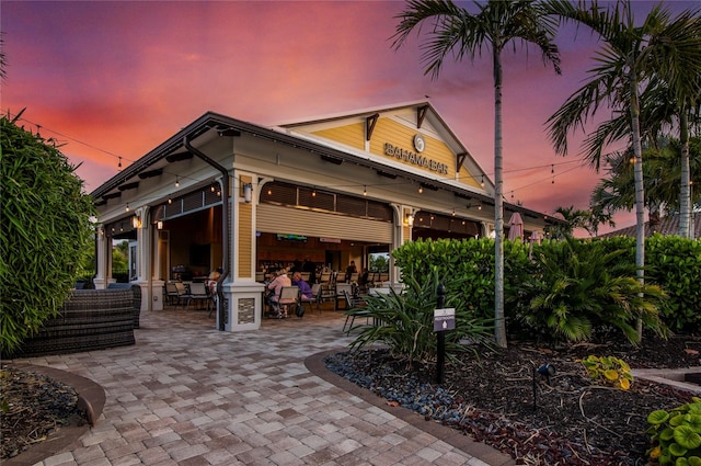 back house at dusk featuring a patio