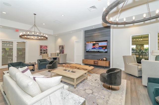 living room with a chandelier, french doors, and wood-type flooring