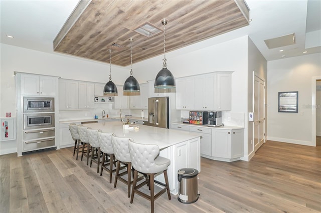 kitchen featuring light hardwood / wood-style flooring, appliances with stainless steel finishes, an island with sink, sink, and wood ceiling