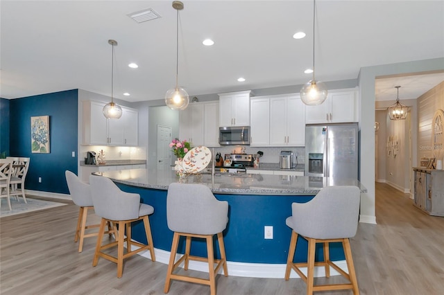 kitchen with decorative backsplash, white cabinetry, an island with sink, and appliances with stainless steel finishes