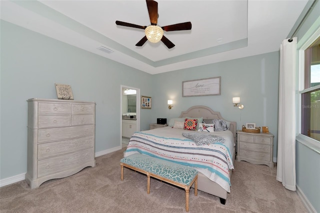 carpeted bedroom with ceiling fan, a raised ceiling, and connected bathroom