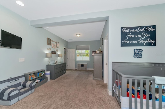 bedroom featuring light carpet and a nursery area