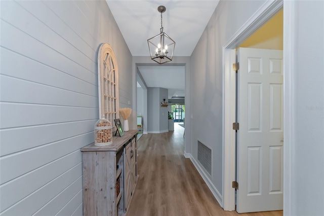 hallway with light hardwood / wood-style floors and a notable chandelier