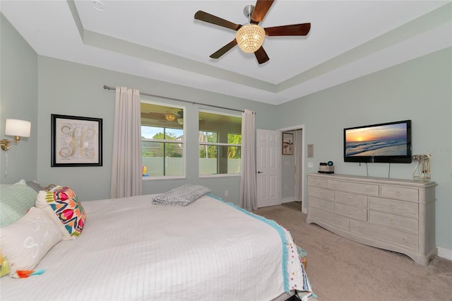 carpeted bedroom with a tray ceiling and ceiling fan