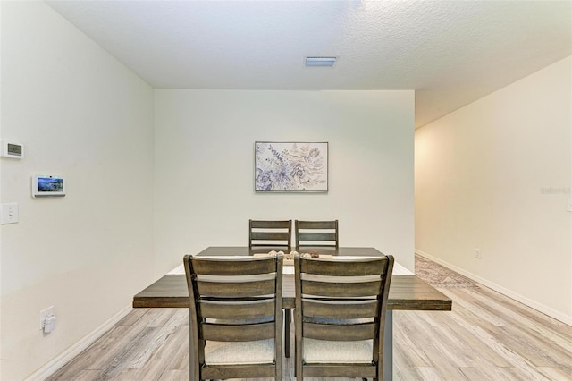 dining room with a textured ceiling and light hardwood / wood-style flooring