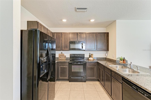 kitchen with sink, dark stone countertops, a textured ceiling, light tile patterned floors, and black appliances