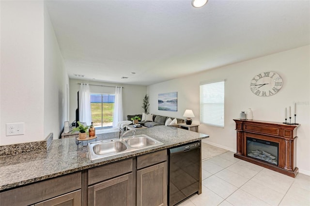 kitchen featuring dishwasher, light tile patterned floors, dark stone countertops, and sink