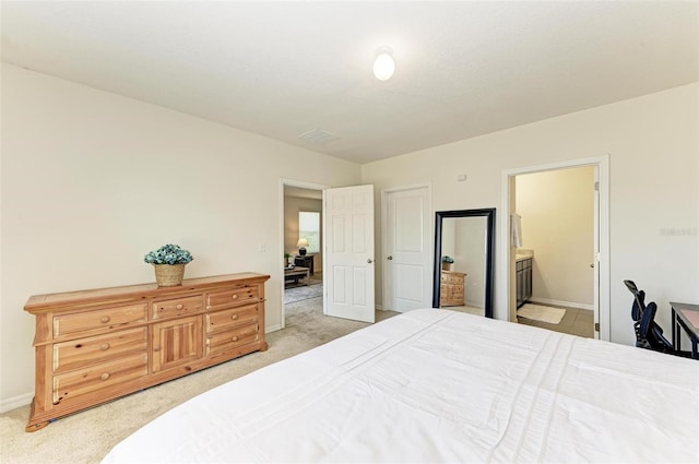 bedroom with light colored carpet and connected bathroom