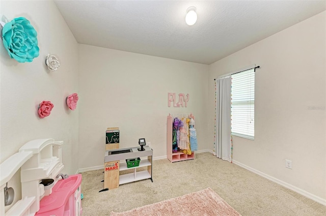 playroom featuring light colored carpet and a textured ceiling