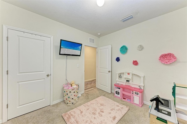 playroom with a textured ceiling and light colored carpet