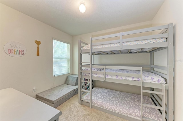 bedroom featuring light colored carpet and a textured ceiling