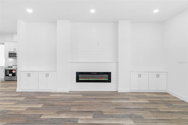 unfurnished living room featuring a large fireplace, light wood-style floors, and recessed lighting