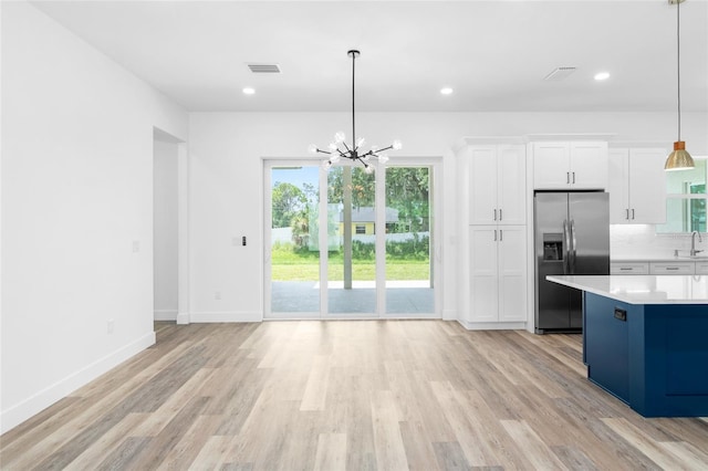 kitchen with light wood-style flooring, visible vents, white cabinets, light countertops, and stainless steel fridge