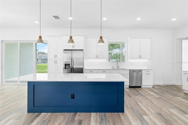 kitchen featuring a center island, stainless steel appliances, tasteful backsplash, visible vents, and a sink