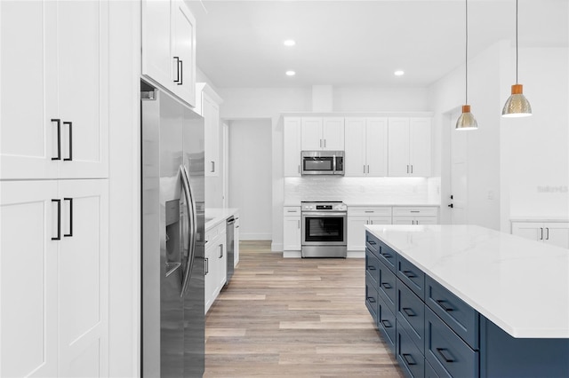 kitchen featuring light wood-style flooring, recessed lighting, stainless steel appliances, white cabinets, and backsplash