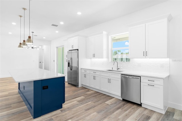 kitchen featuring a center island, a sink, stainless steel appliances, light wood-style floors, and backsplash