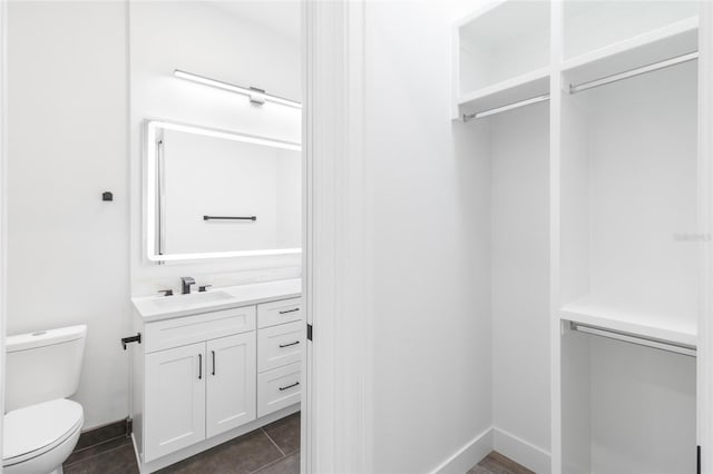 spacious closet featuring dark tile patterned floors and a sink