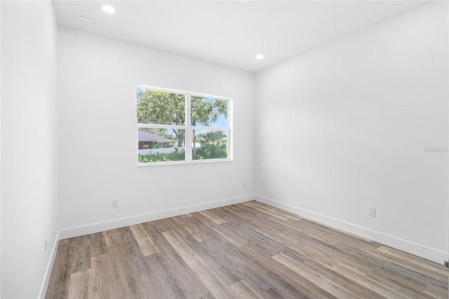 spare room featuring baseboards, wood finished floors, and recessed lighting