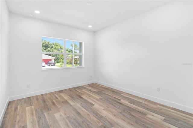 empty room with recessed lighting, light wood-style flooring, and baseboards