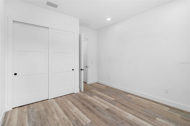 unfurnished bedroom with baseboards, visible vents, wood finished floors, a closet, and recessed lighting